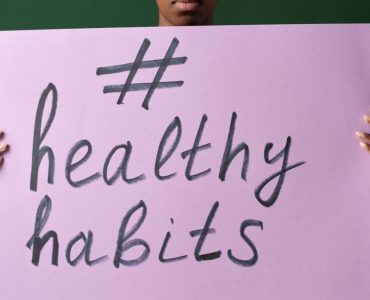 Person holding a "#healthyhabits" sign, emphasizing wellness.