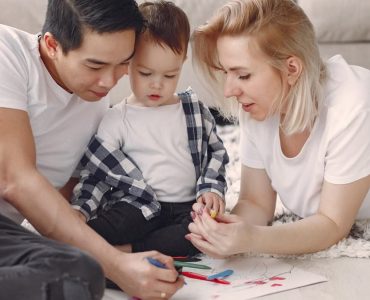 Loving family creating art together, fostering play and connection indoors.