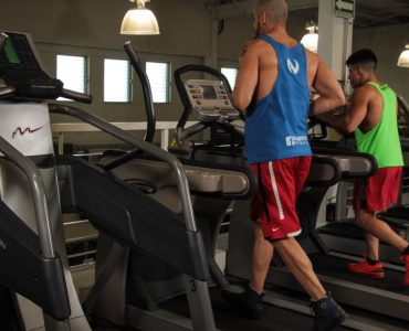 Two men running on treadmills in a modern gym, promoting fitness and health.