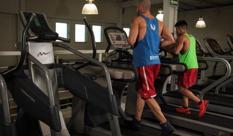 Two men running on treadmills in a modern gym, promoting fitness and health.